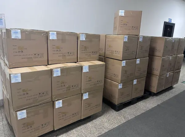 Bulk shipment staging area with stacked export cartons containing 10,000-unit annual production of payment terminals prepared for ocean freight